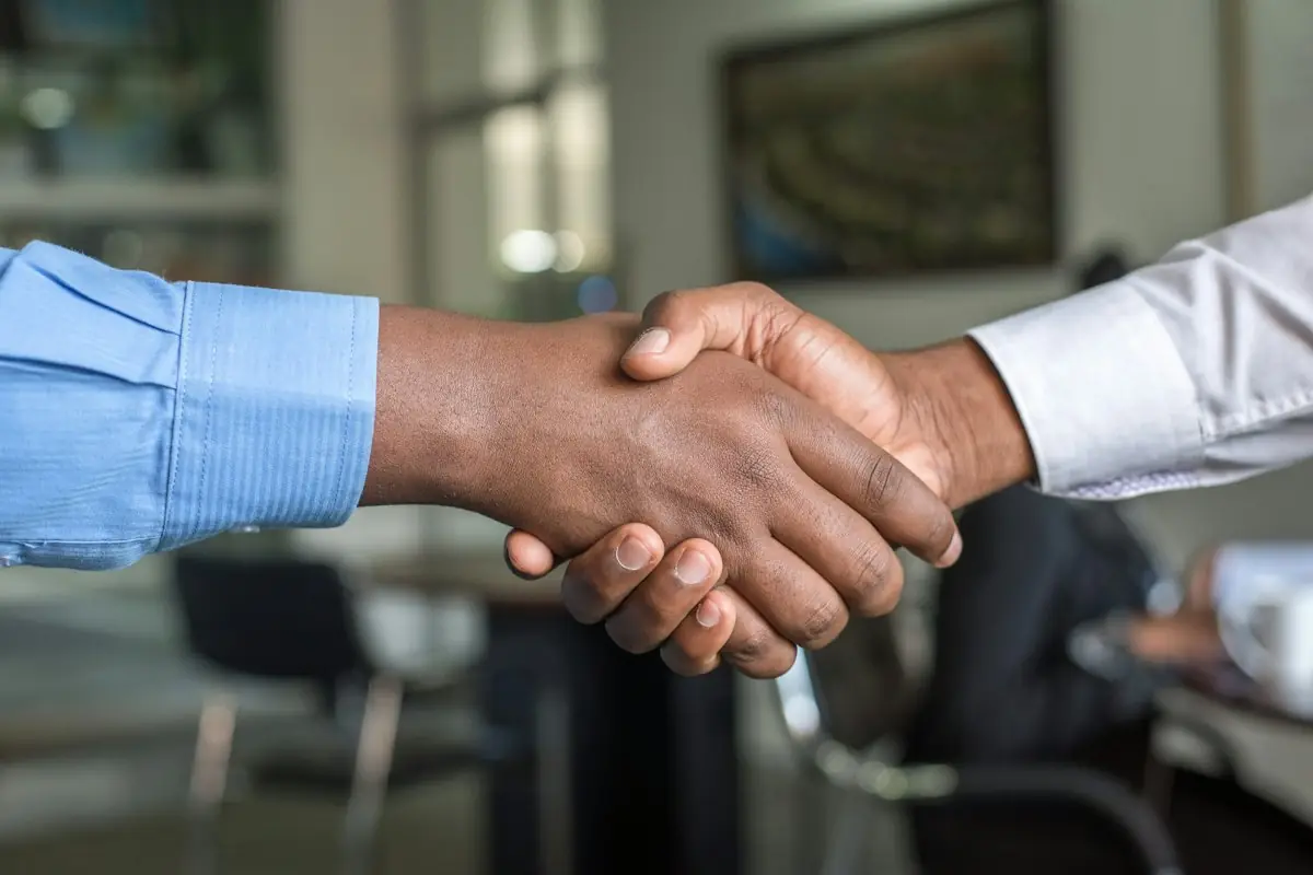 Employer and recruiter shaking hands across a desk